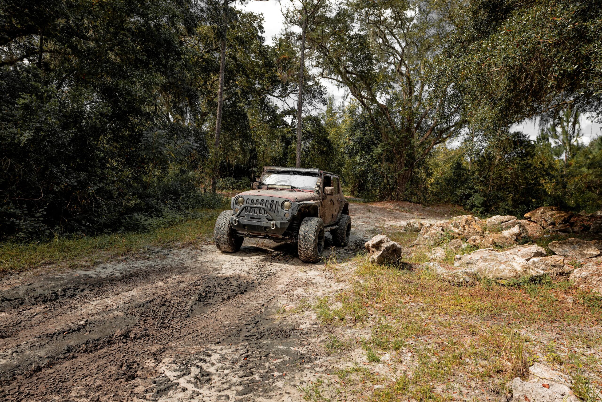 A rugged Jeep driving along a remote off-road trail surrounded by trees and natural terrain, illustrating outdoor adventure and off-roading.