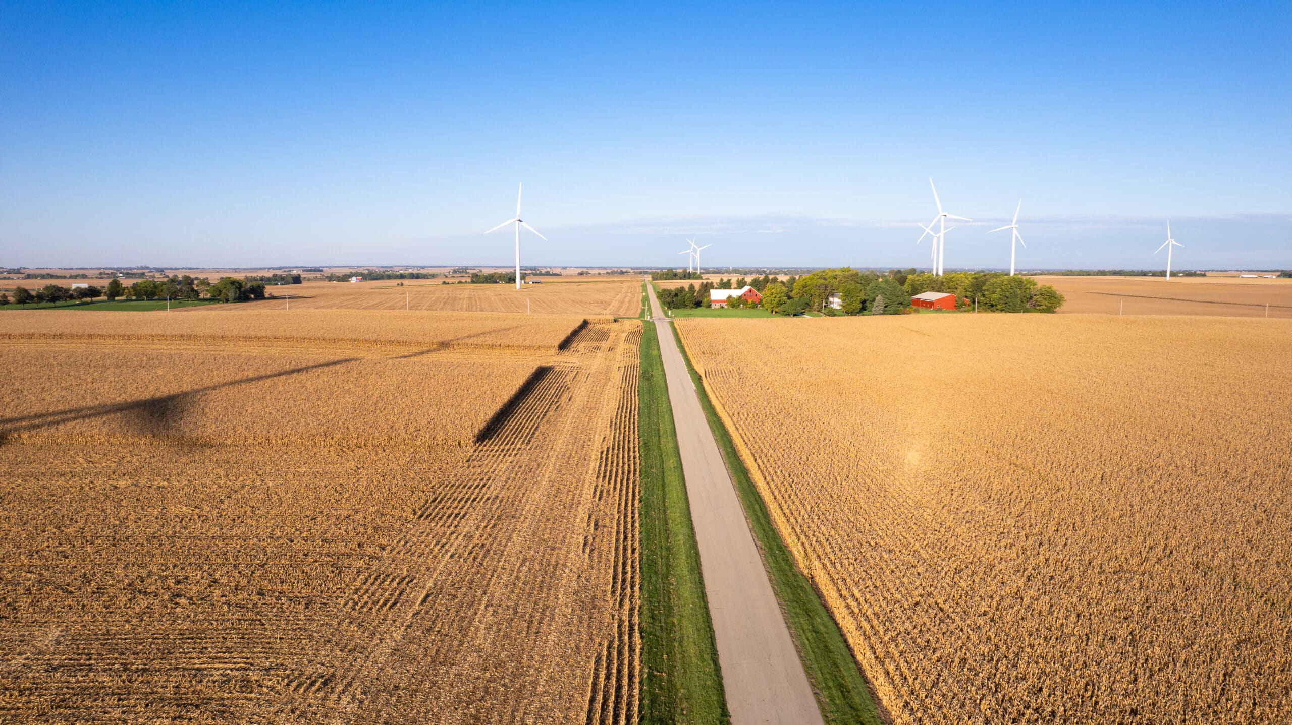 Illinois farmland for sale showing productive crop fields, rural road access, and renewable energy wind turbines